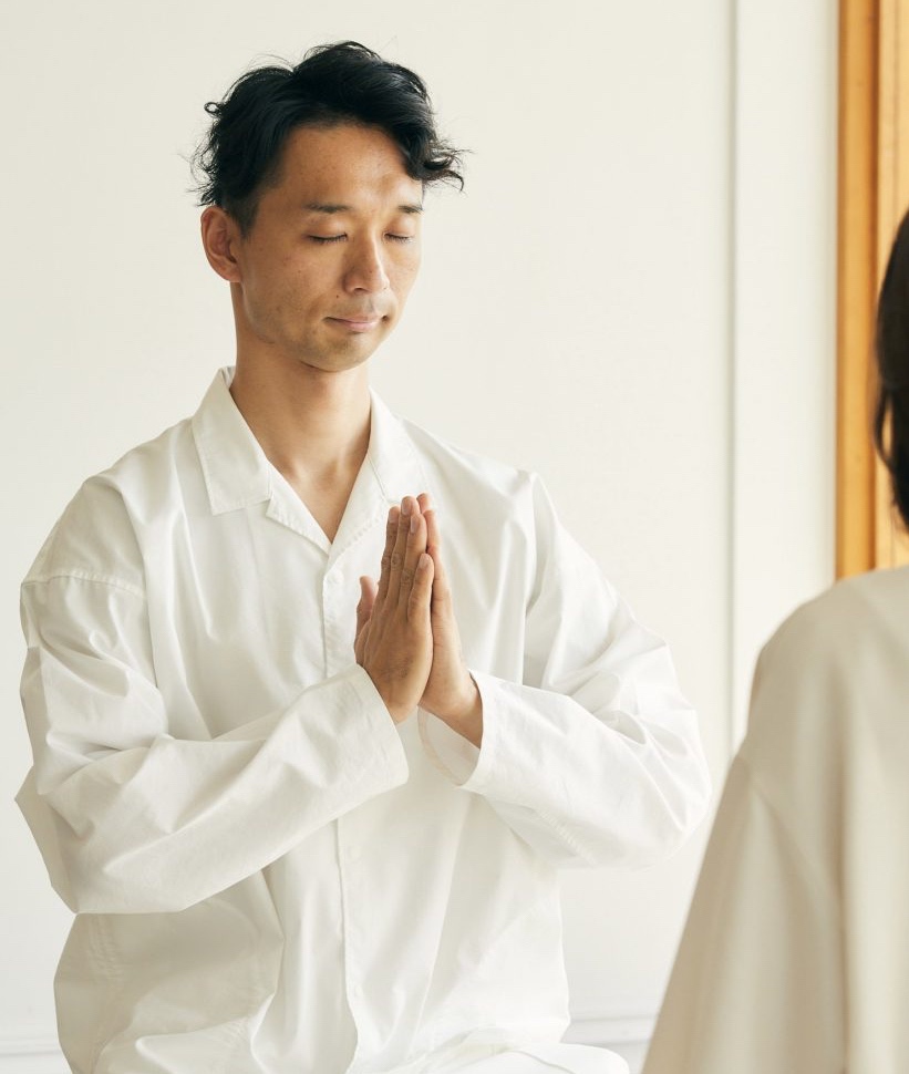 ３０代の男性が白いシャツを着てマインドフルネス瞑想をしている